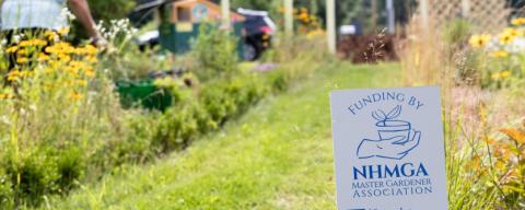 A garden with a sign saying it was supported by the NH Master Gardeners Association