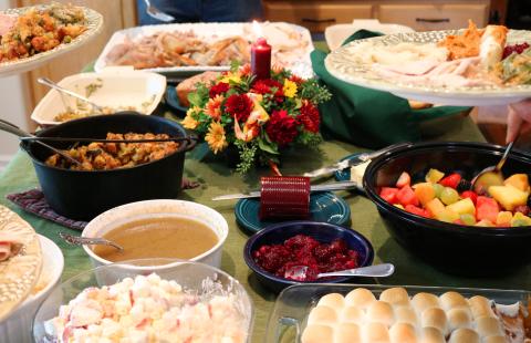 Casual holiday feast on table with plates being filled.