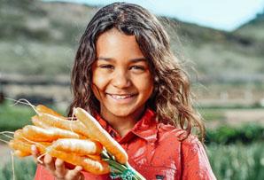 Girl holding a bunch of freshed picked carrots