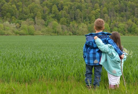 Children embracing in a field